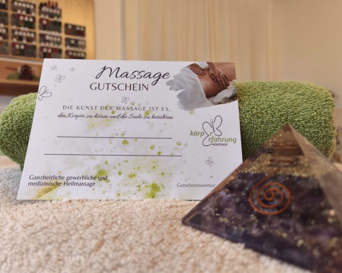 Massage-Gutschein von Körpererfahrung Massage auf einem Handtuch im Praxisraum, mit grünem Badetuch und dekorativer Edelstein-Pyramide im Vordergrund – Symbol für ganzheitliche Heilmassage und Entspannung.